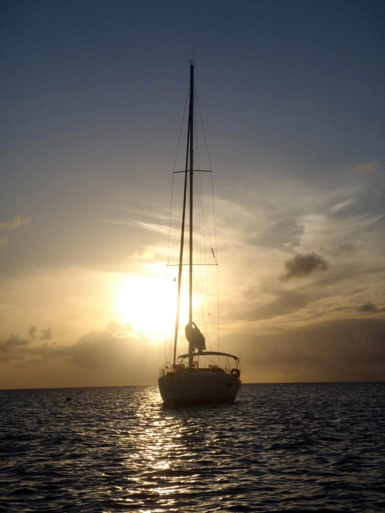 sun behind sailboat at anchor
