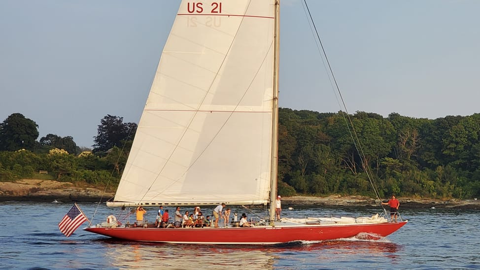 A team of sailors in a red sailboat in Newport